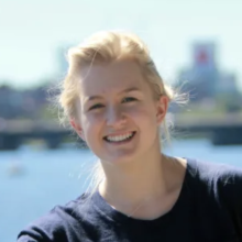 A smiling woman, Grace Young, with blonde hair and a black shirt looks at the camera