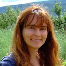 Photo of Annette Govindarajan a white woman with red hair wearing a white shirt and blue cardigan