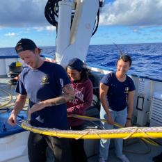 Three people work on tying knots on a backdeck