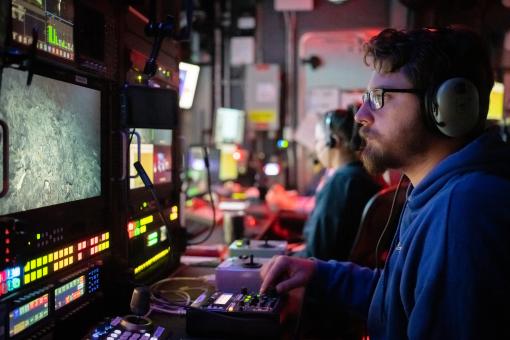 Picture of a man in the Nautilus control room viewing seafloor footage of ROV dive 